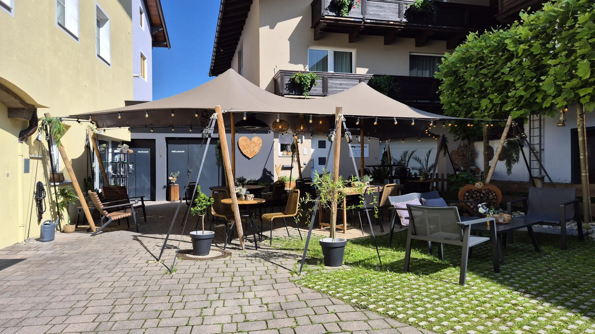 Gemütlicher Außenbereich mit Sonnenschutz, Pflanzen und Sitzgelegenheiten.