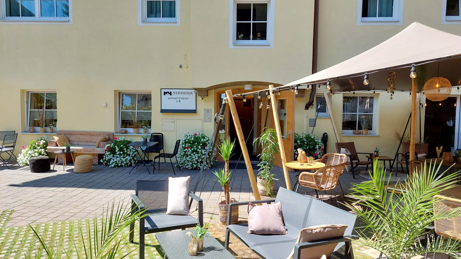 Ein Innenhof mit Sitzgelegenheiten, Pflanzen und einem Sonnenschirm.