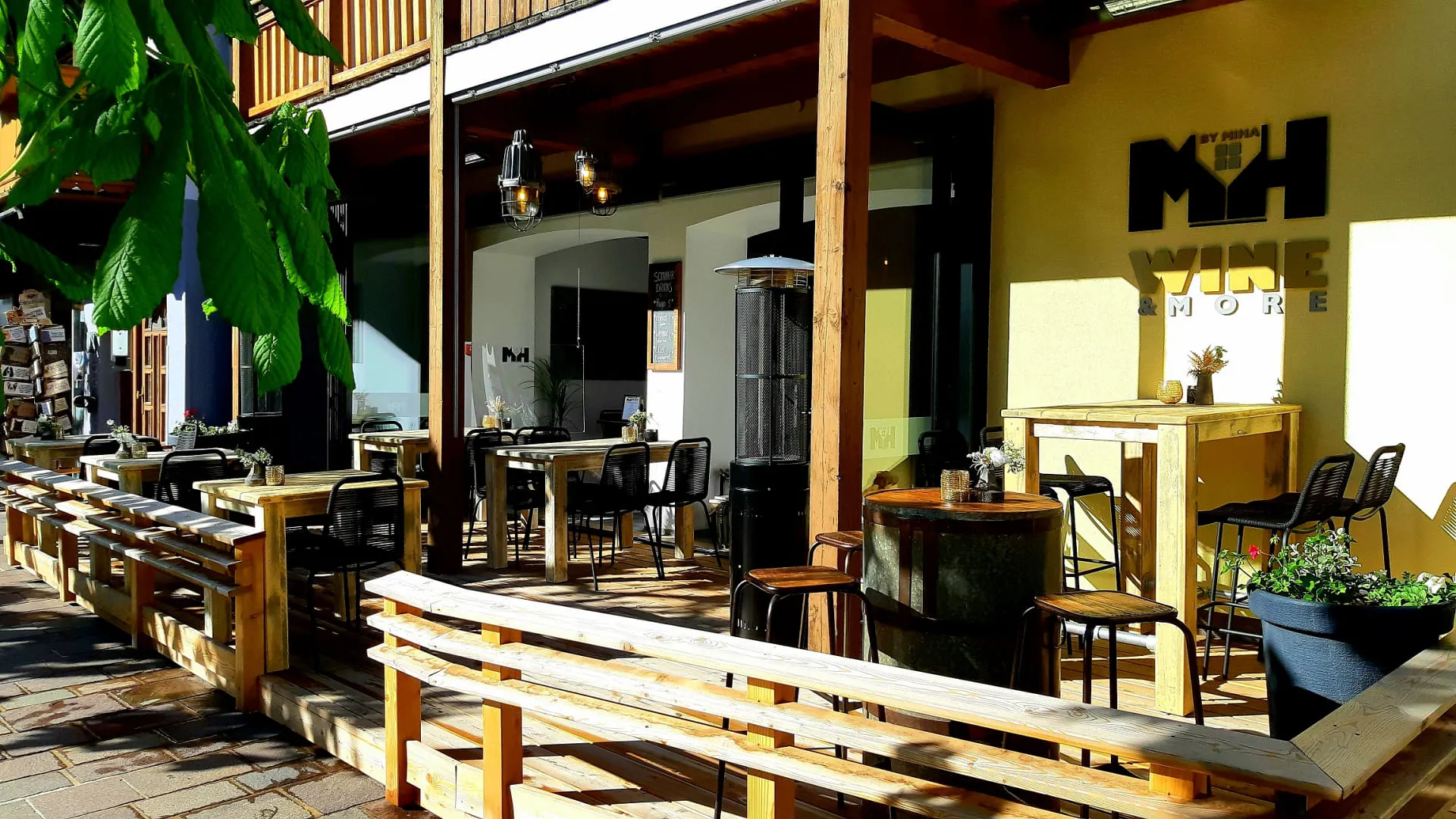 Terrasse von Wine & More mit Holzmöbeln und Pflanzen